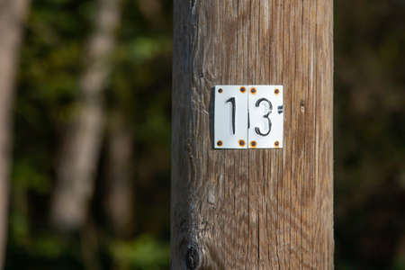 Sheet metal with the number 13 on a wooden mast, outdoors
