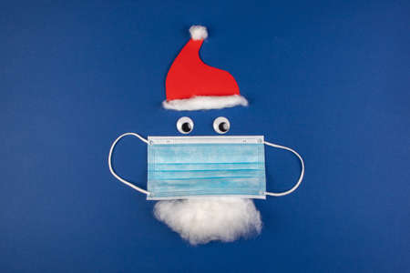 handmade santa clause with moth protection, face mask, red cap and beard, as a symbol for impact in...
