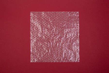 plastic wrap on a red background, view from above