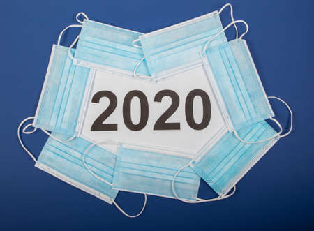 year number 2020 surrounded by mouth protection on blue background, symbol for this year under...