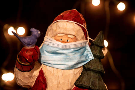 Santa Clause figurine wearing a mouth protection as symbol for impact of Covid-19 virus to Christmas celebration 2020, conceptの写真素材