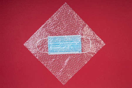 blue mouthguard under a plastic wrap on a red background, shot from above