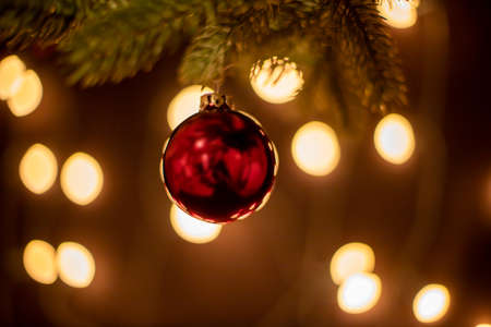 red christmas ball on a pine branch, lights in the background, reflection in the ballの写真素材