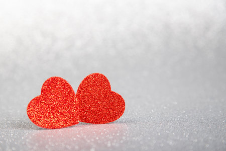 two red hearts in glitter on a silver and red glitter background, valentine's dayの写真素材