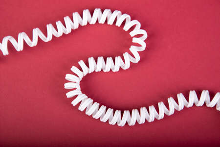Coiled white wire runs through the picture, red backgroundの写真素材