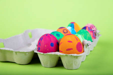 painted eggs with easter motives in an egg carton, green backgroundの写真素材