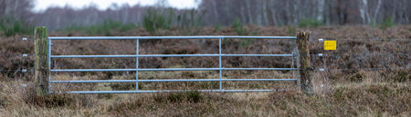 Lattice gate in a heather landscape, a sign at the fence warns in German letters before electricityの写真素材