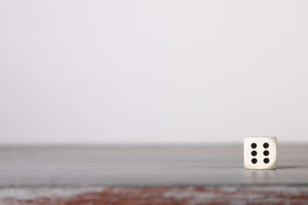 the dice have fallen, one white dice on a gray wooden board