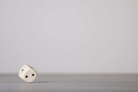 the dice have fallen, one white dice on a gray wooden boardの写真素材