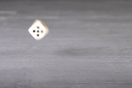 the dice have fallen, one white dice on a gray wooden board