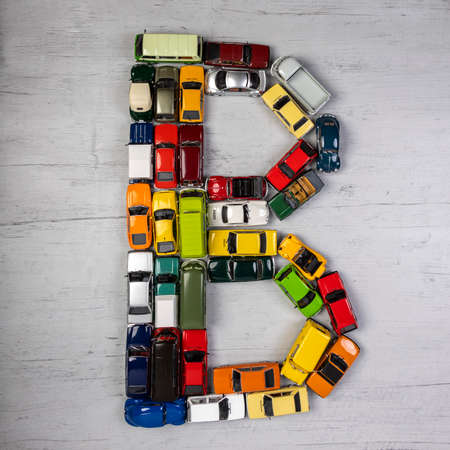 the letter B, formed with toy cars, on a gray wooden boardのeditorial素材