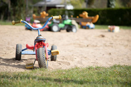 Children's tricycle and other toys in a park, no peopleの写真素材