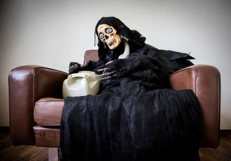 telephoning toy skull in a brown leather seat, symbol for waiting a life time at a hotlineの写真素材