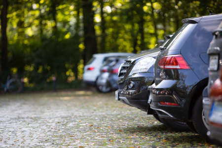Parking cars in a parking lot with paving stones, surrounded by treesのeditorial素材