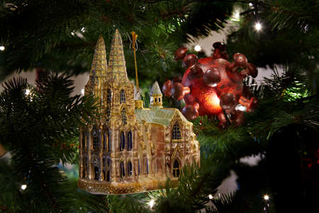 Cologne cathedral ornament and a model of a covid-19 virus in a christmas tree surrounded my lights, symbol of impact of corona virus on christmas seasonの写真素材