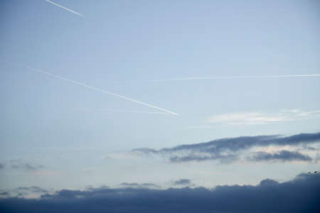 condensation trail of a plane at sunrise in the blue sky, cloudsの写真素材