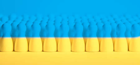 wooden figurines in blue and yellow as symbol for people in Ukraine and refugees