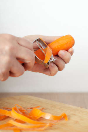 woman's hands removing the outer layer of a carrot with a julienne cutterの写真素材