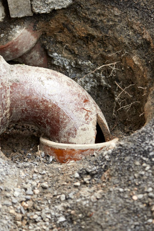 clay sewer pipe with hole, broken, exposed in the groundの写真素材
