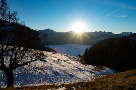 Shortly before sunset: Snow covered alpine meadows and a valley in the fogの写真素材