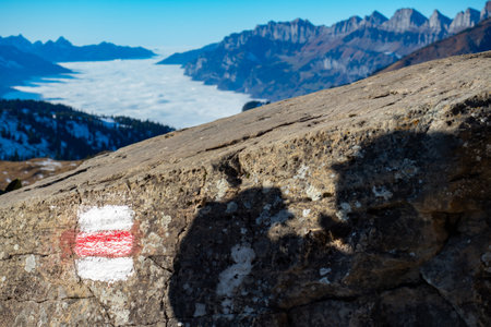 Swiss Alps above Walensee: Shadow of a hiker and view into a valley full of fogの写真素材