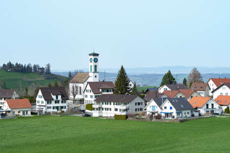 View of the village Schoenenberg, Switzerland, with surrounding fields and hillsの写真素材