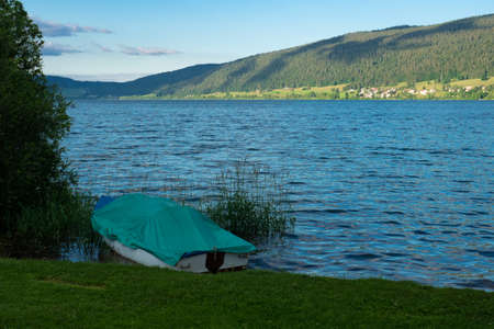 A motor boat lying on the banks of Lac de Joux, Switzerland, in afternoon sunlightの写真素材