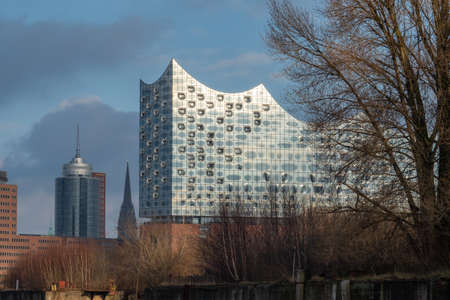 Hamburg, Germany - December 29th 2018: Facade of Elbphilharmonie behind trees and in front of the city centreのeditorial素材