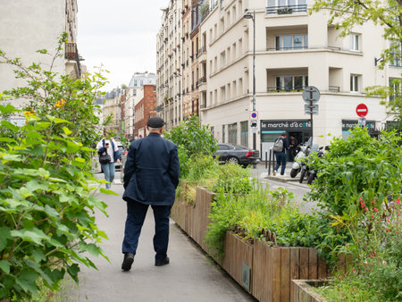 Paris, France - May 11th 2023: Green urban space in the city - an old man walking over the bridge of Rue du Ruisseauのeditorial素材