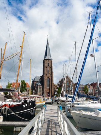 Harlingen, Netherlands - August 7th 2023: Marina with sailboats in front of the city churchのeditorial素材