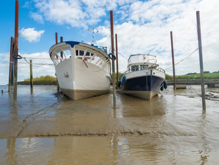Ditzum, Netherlands - August 10th 2023: Motor vessels lying on the ground during low water tide.のeditorial素材