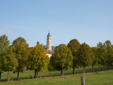 Neresheim, Germany - September 30th 2023: The church tower of the famous monastery behind colourful treesの写真素材