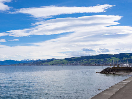 Arbon, Switzerland - March 29th 2024: At the bank of Lake Constance in front of the Alps with...