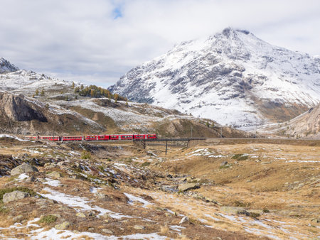 Bernina, Switzerland - October 5th 2024: Red train of Bernina Express in high alpine surrounding