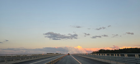 Car on the bridge in the evening with clouds and blue sky.