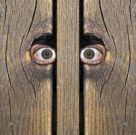 Eyes watching something through hole in a fenceの写真素材