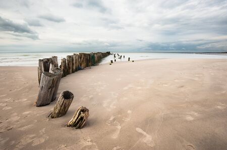 Poles on a line into the sea on the beach in Denmarkの写真素材