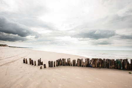 Poles in the sand at the beach in Tversted in Denmarkの写真素材
