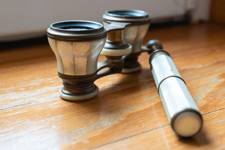 Very old binoculars lays on the wooden floor. Elegant and noble signs of a precious pastの写真素材