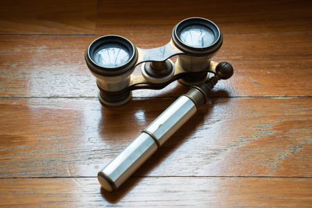 Very old binoculars lays on the wooden floor. Elegant and noble signs of a precious pastの写真素材