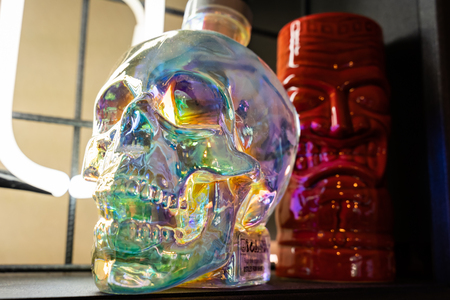 A bottle with the shape of a skull with colorfull light reflectionの写真素材