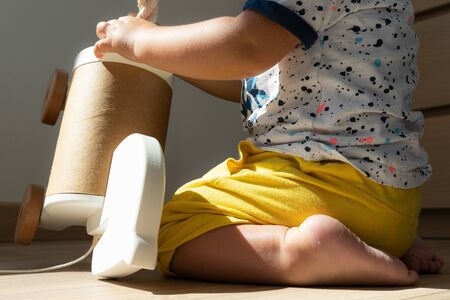 A little child plays alone, crourched on the floor, with sweet feet and tiny fingersの写真素材