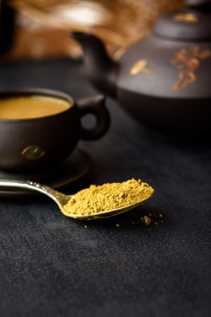 Spice for masala tea in a spoon. Traditional Indian hot drink with milk and spices on dark background close upの写真素材