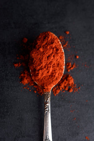 Top view of red paprika powder in spoon on black background with copy spaceの写真素材