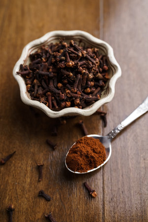 Dried and powdered cloves on a wooden tableの写真素材