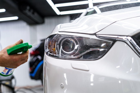Sticker of a protective film on the headlight of a car in a car detailing studioの写真素材
