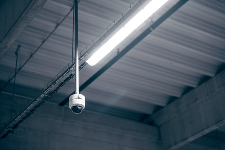Digital surveillance camera on the ceiling in a warehouse room