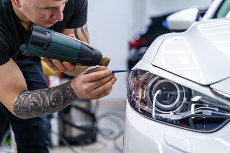 Sticker of a protective film on the headlight of a car in a car detailing studioの写真素材