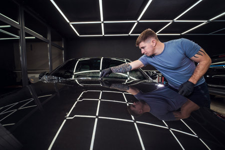 Sticker of a protective film on the headlight of a car in a car detailing studioの写真素材