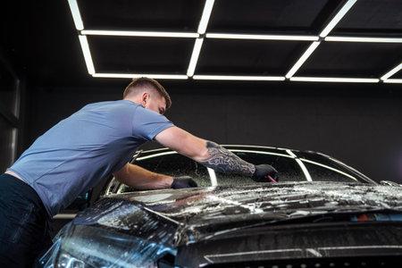 Sticker of a protective film on the headlight of a car in a car detailing studioの写真素材